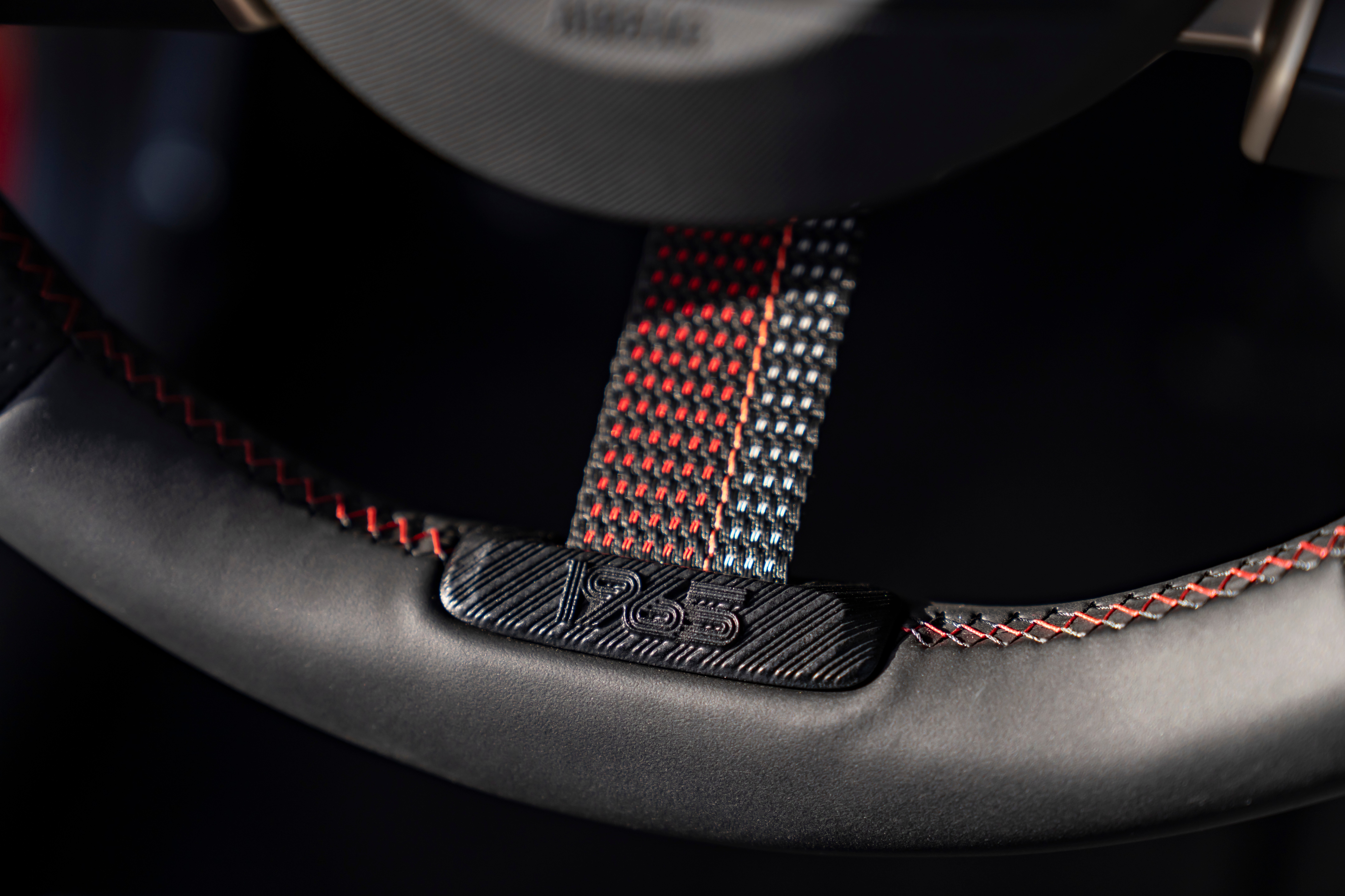 Détail du volant avec surpiqûres rouge‑noir et marquage « 1965 »